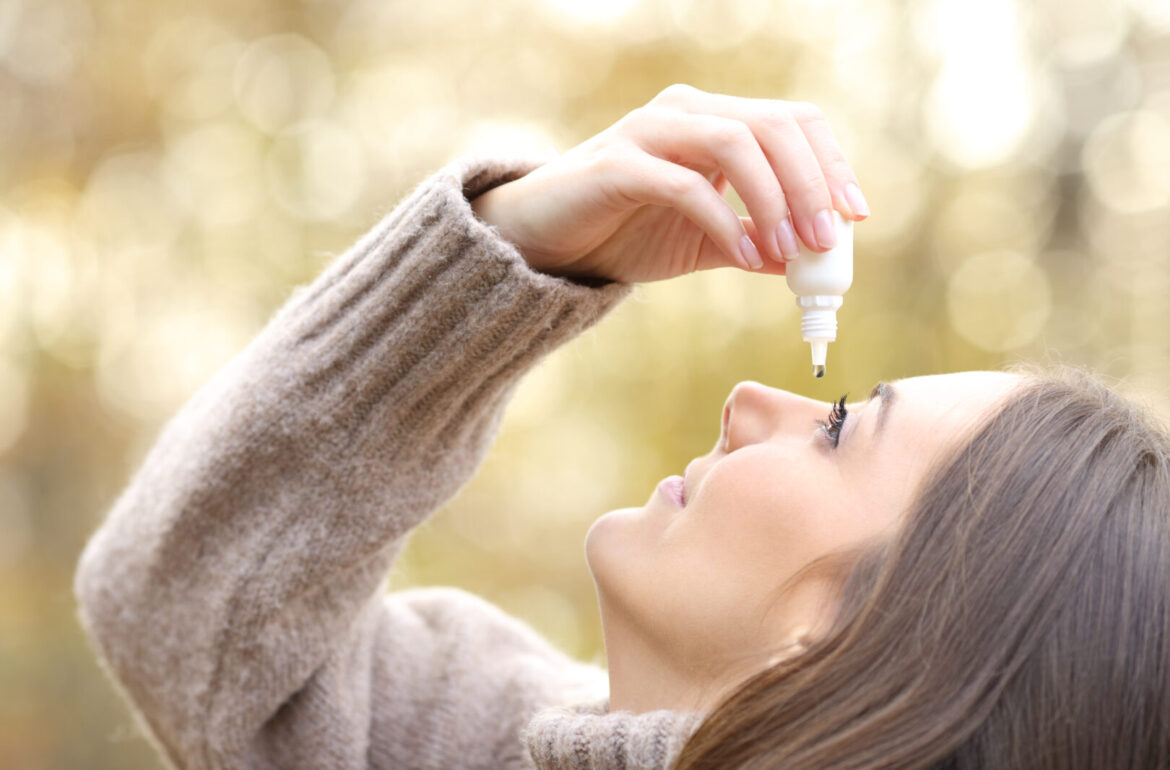 how to get rid of winter allergies: Woman with dry eyes applying artificial tear in winter
