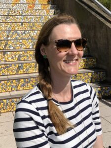 woman smiling outside in a striped shirt with polarized sunglasses for UV eye protection