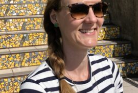 woman smiling outside in a striped shirt with polarized sunglasses for UV eye protection